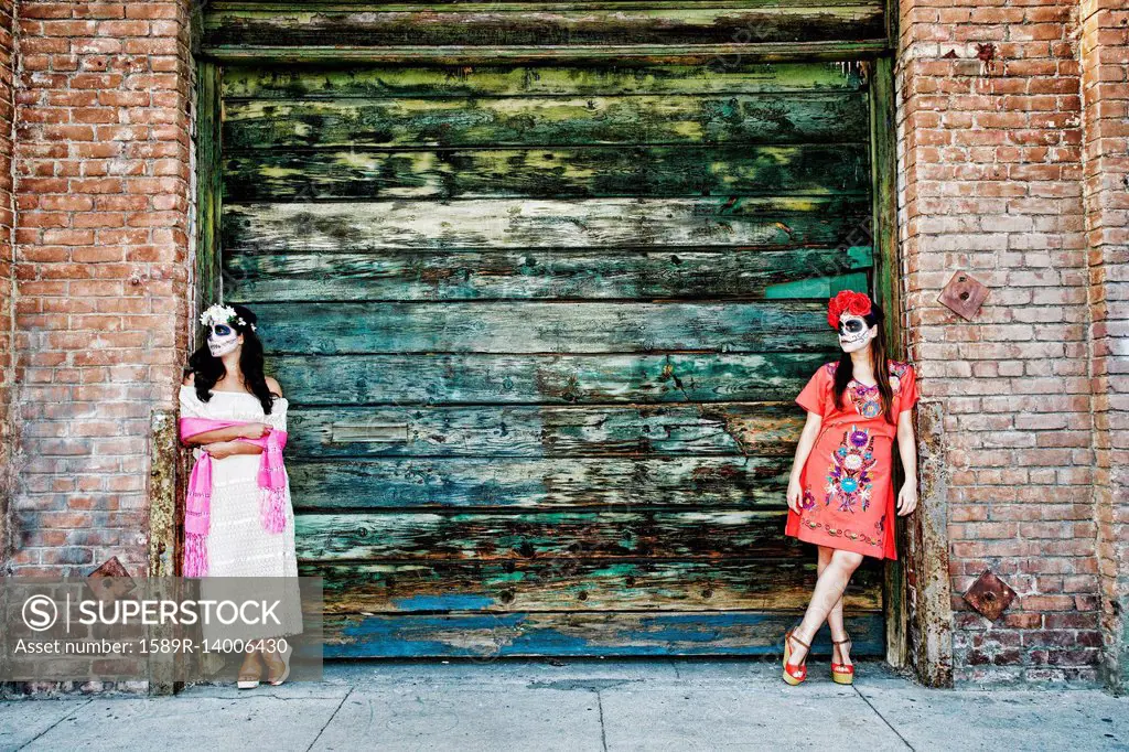 Women leaning on loading dock wearing skull face paint
