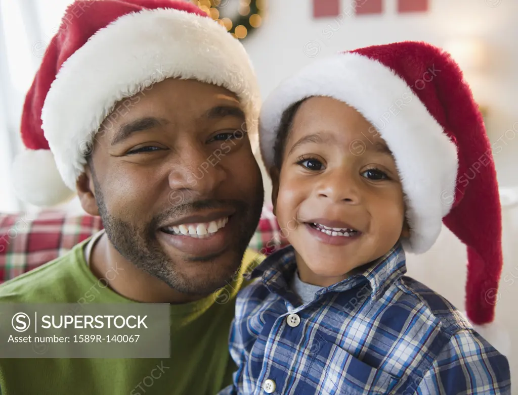 Black father and son wearing Santa hats