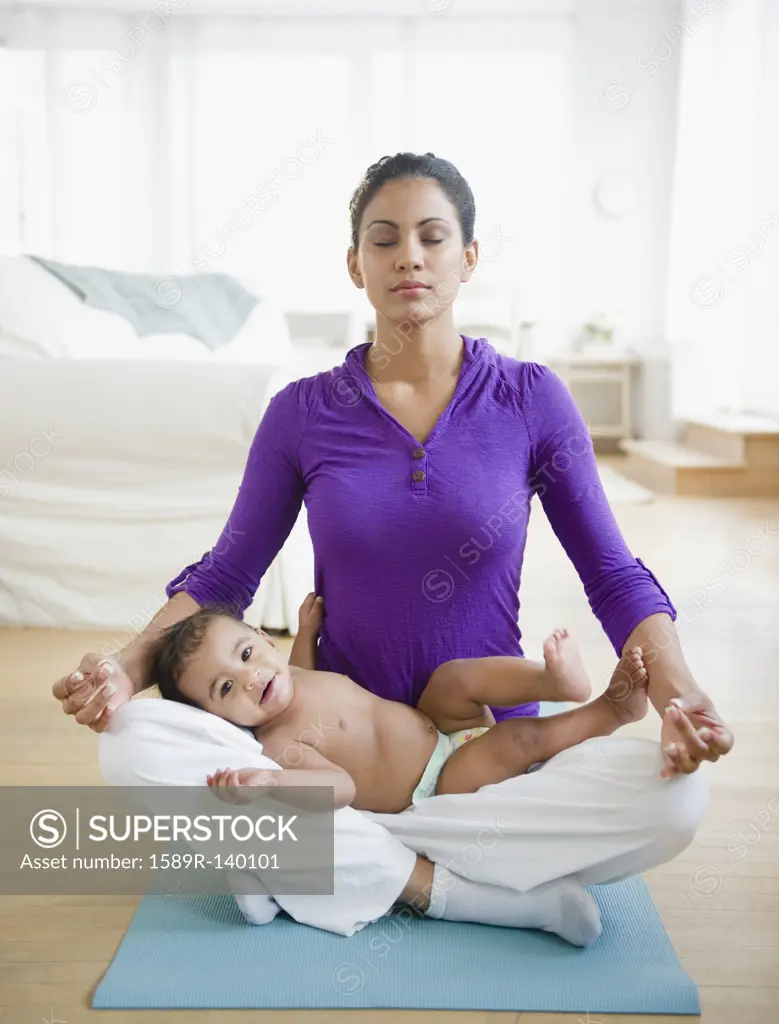 Mother practicing yoga with baby in lap