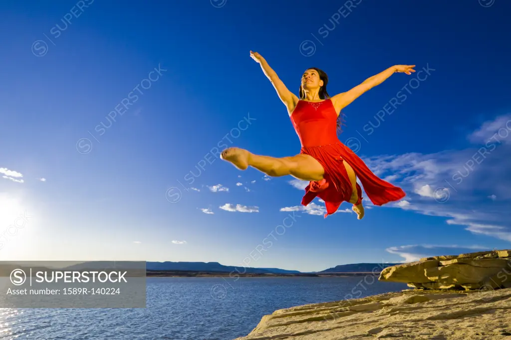 Hispanic woman dancing near lake
