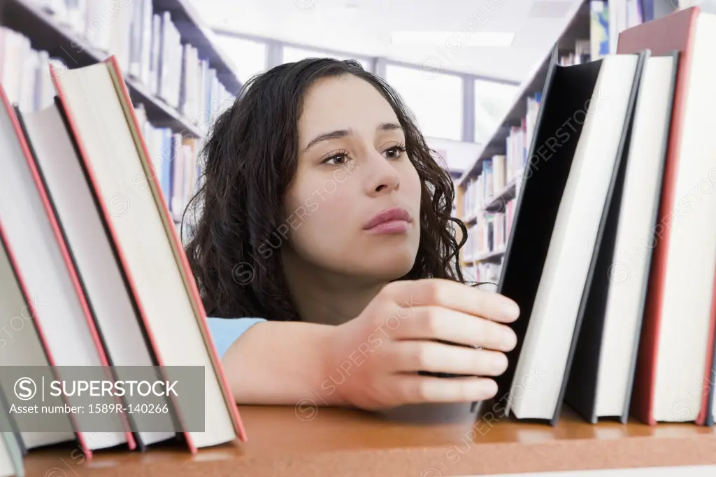 Mixed race woman looking for book in library