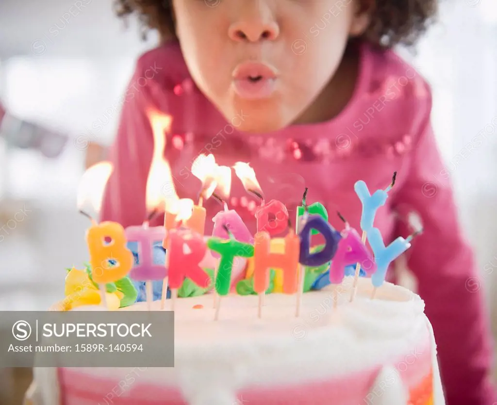 African American girl blowing out birthday candles
