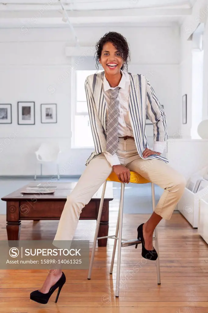 Smiling Mixed Race businesswoman sitting on stool