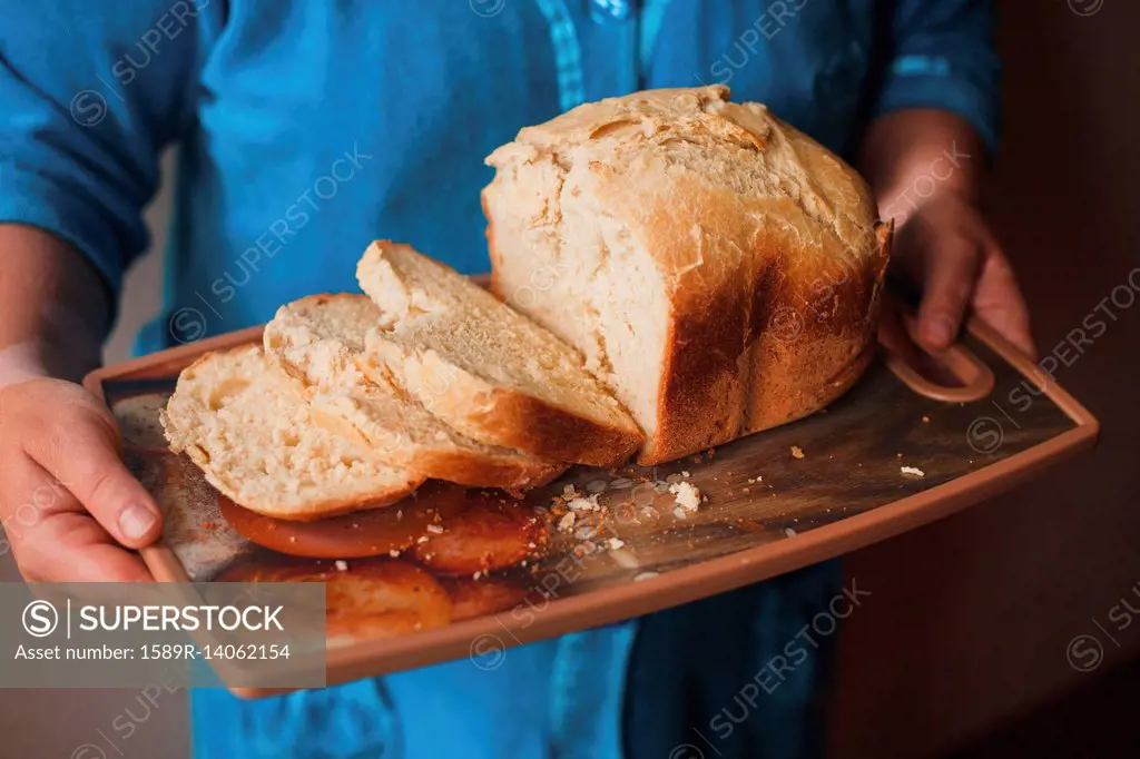 Hands holding tray of sliced bread