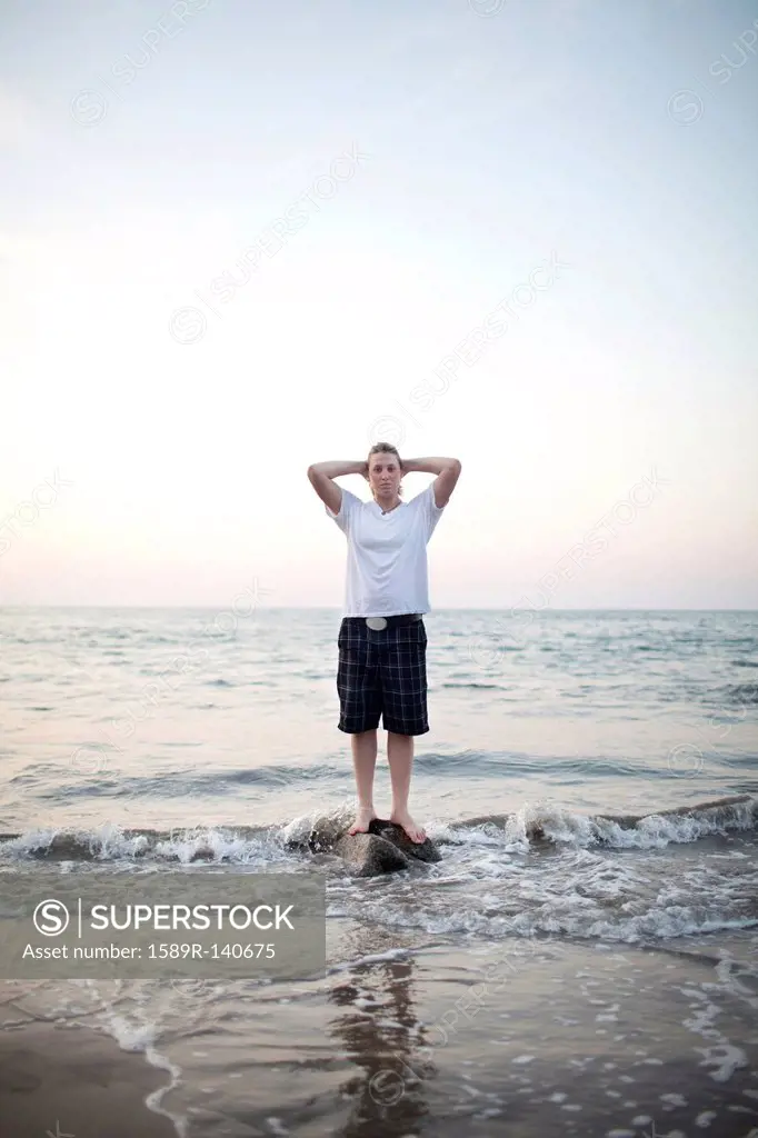 Caucasian woman standing on rock in ocean