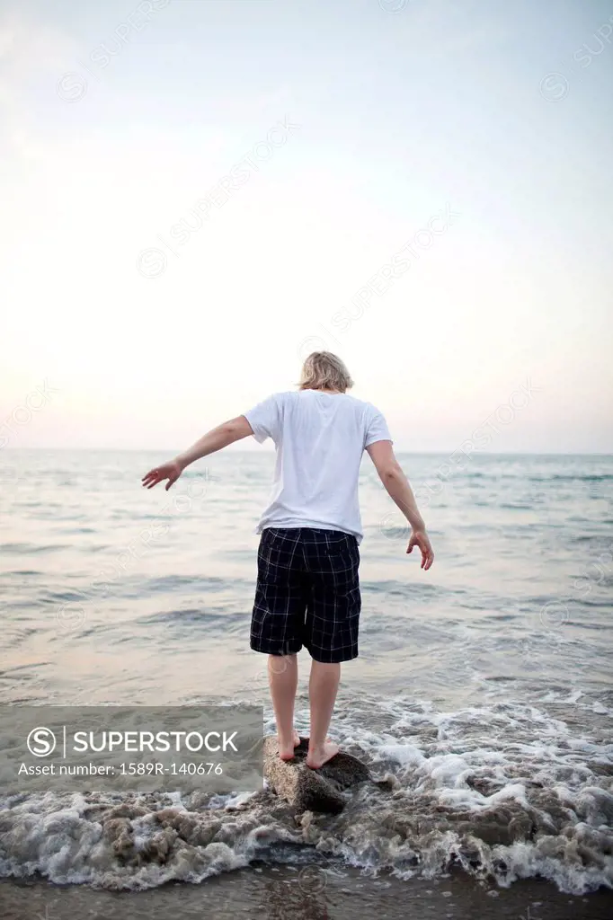 Caucasian woman standing on rock in ocean