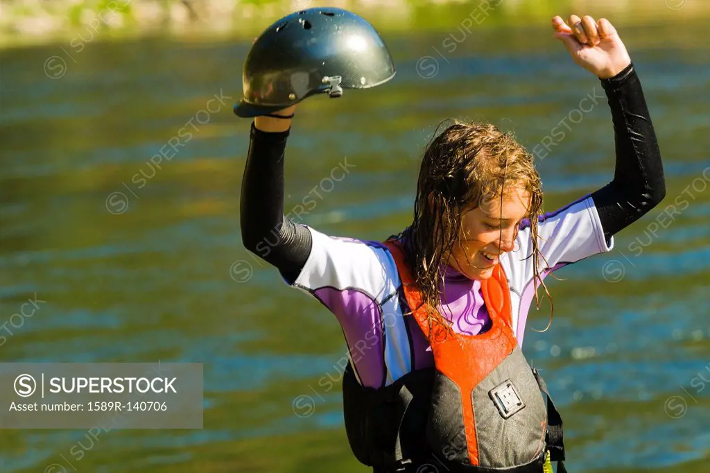 Wet Caucasian girl standing in river in kayak gear