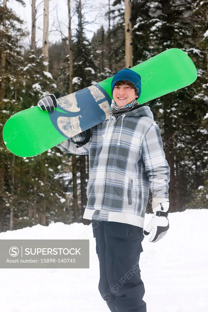 Mixed race snowboarder carrying snowboard