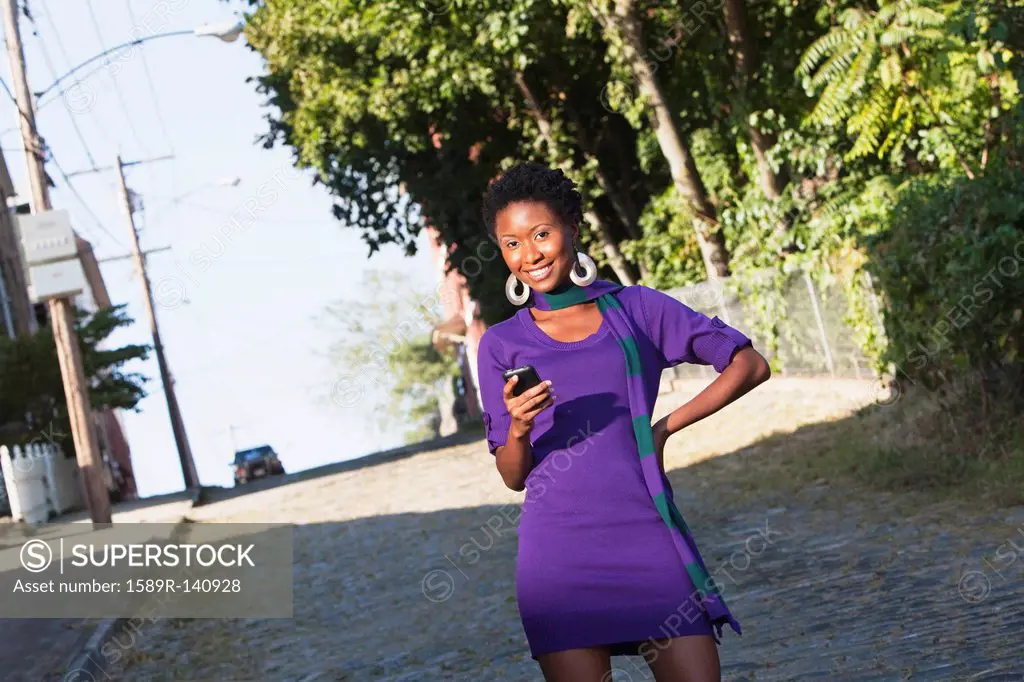 African American woman text messaging on cell phone outdoors