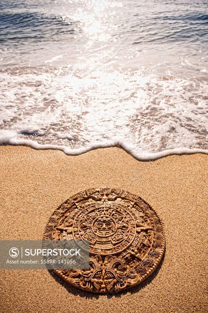 Aztec calendar stone carving on sandy beach