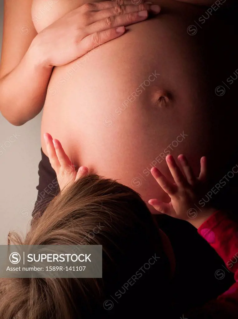 Child patting pregnant mother´s stomach