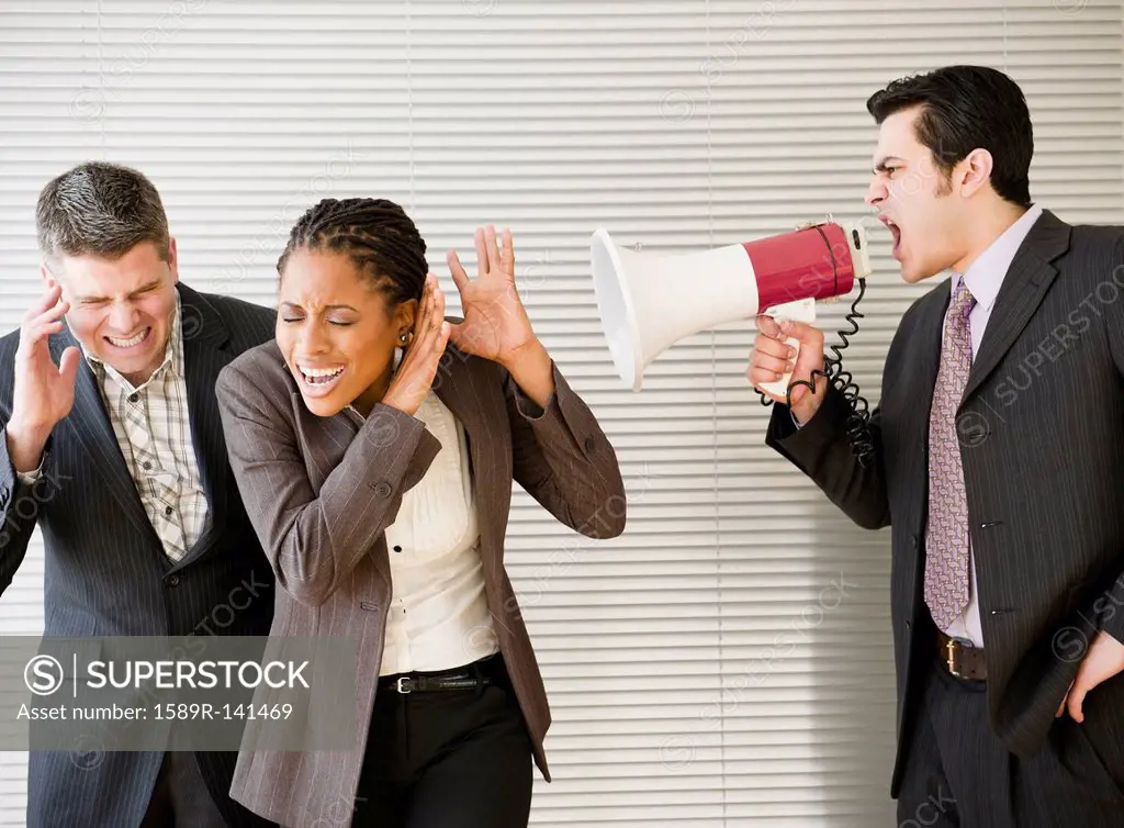 Businessman shouting through bullhorn at co_workers