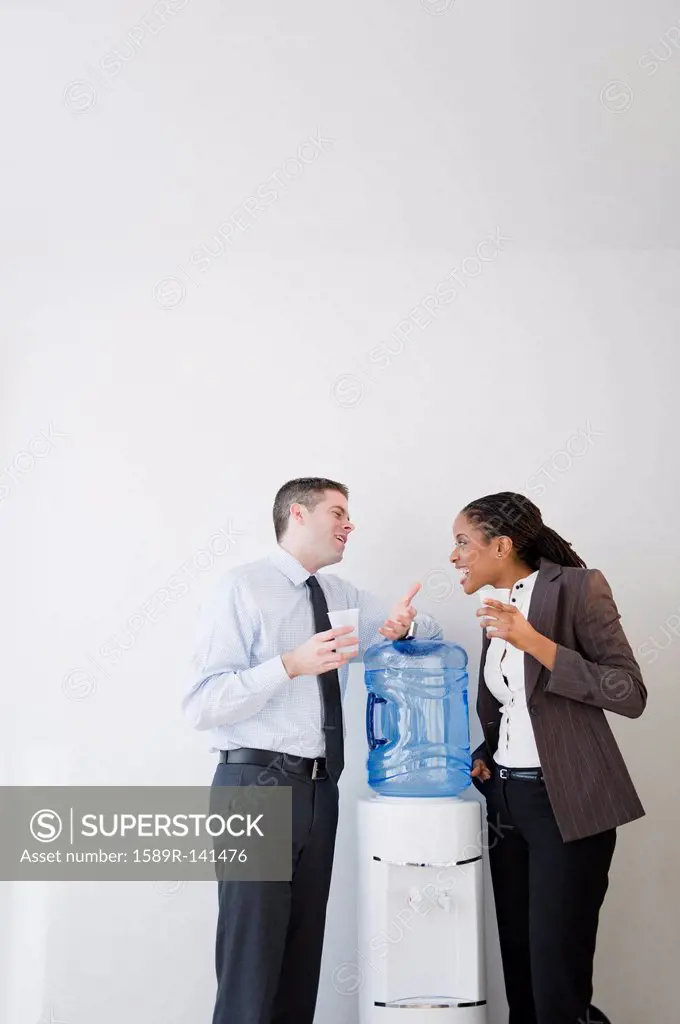 Business people talking together at water cooler