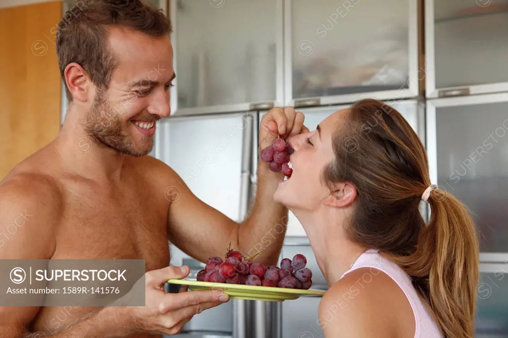Caucasian man feeding wife grapes