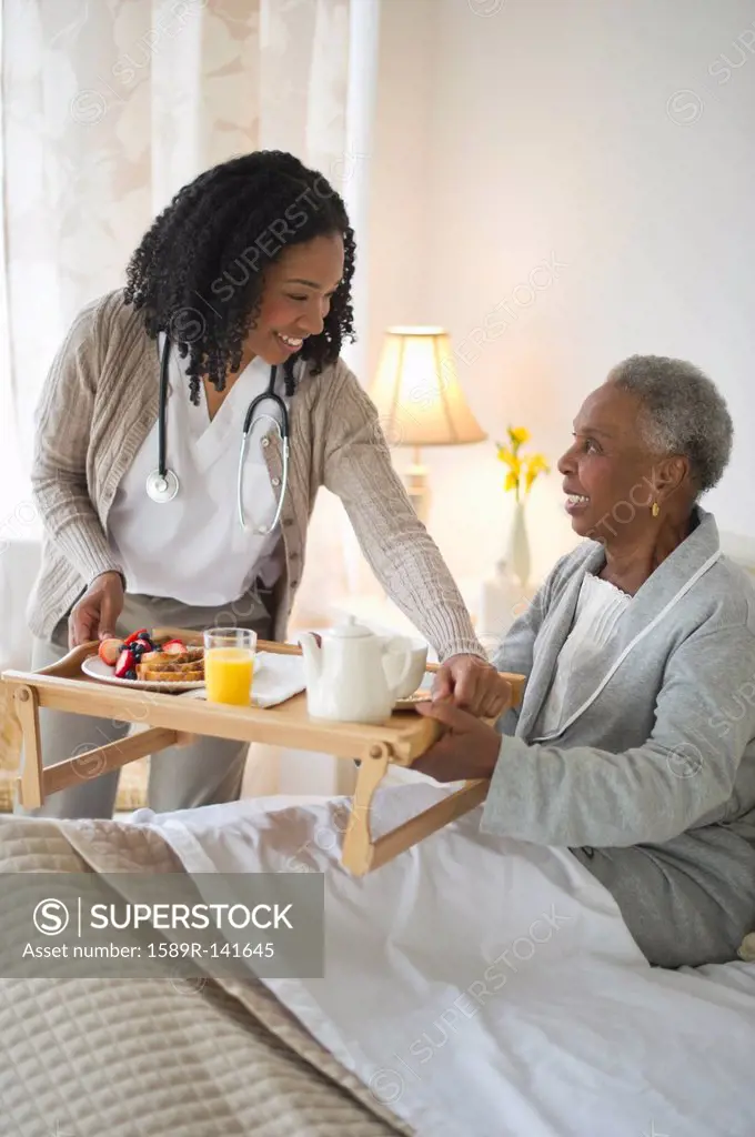 Nurse serving woman breakfast in bed