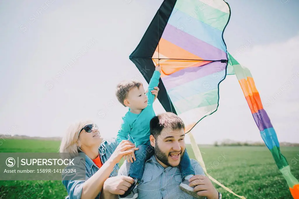 Caucasian boy flying kite with father and grandmother
