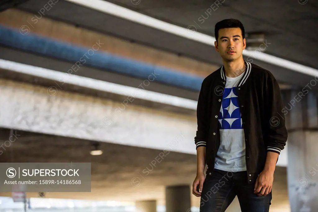 Chinese man standing under urban overpass