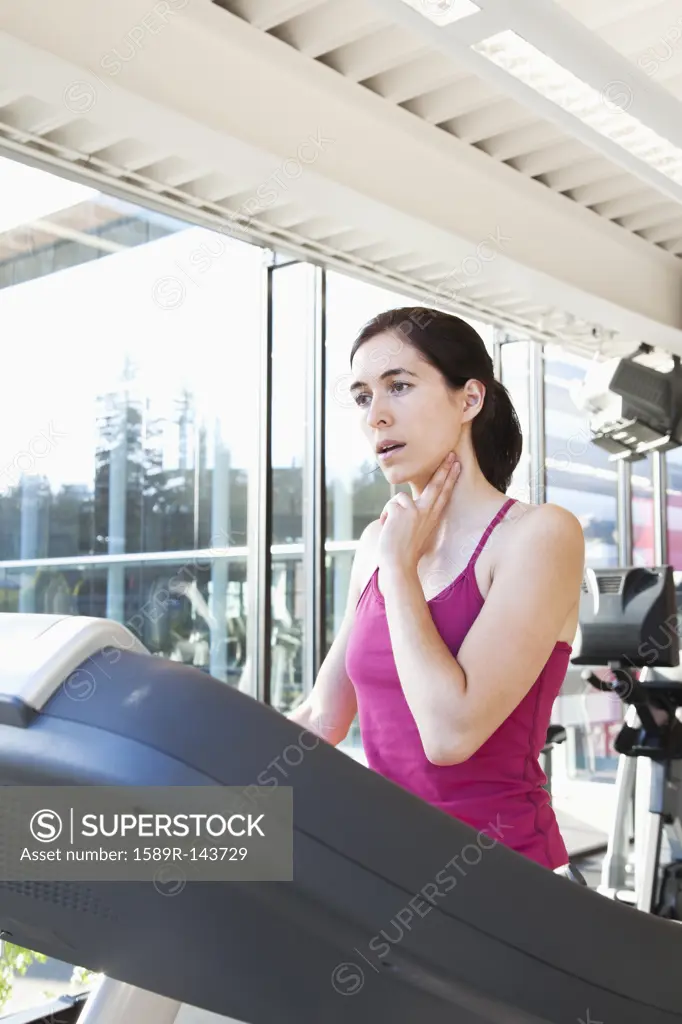 Woman on treadmill checking her pulse