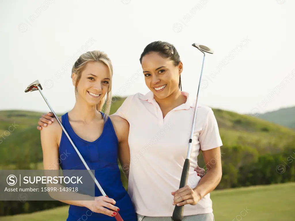 Women with golf clubs hugging on golf course