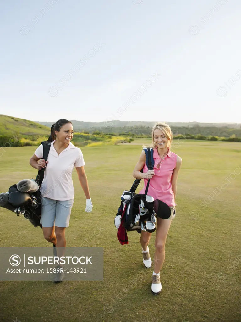 Women carrying golf bags on golf course