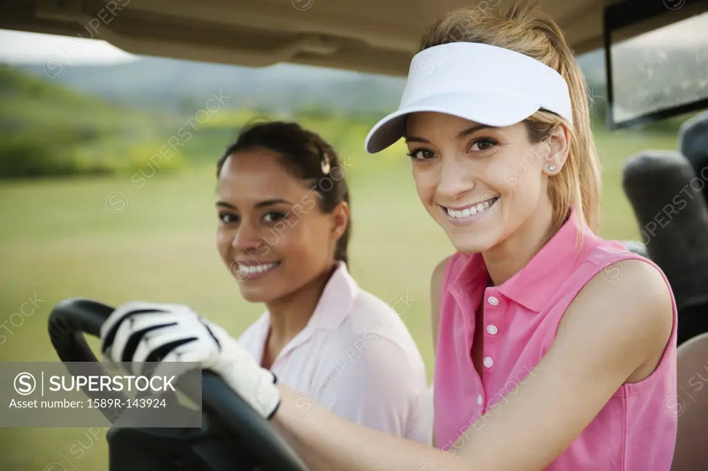 Women driving golf cart on golf course