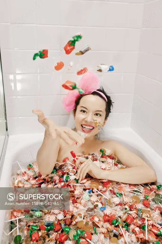 Mixed race woman taking a bath in candy