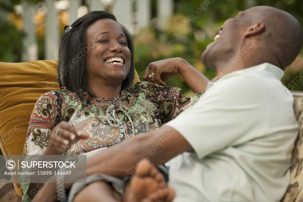 Laughing African American couple sitting outdoors