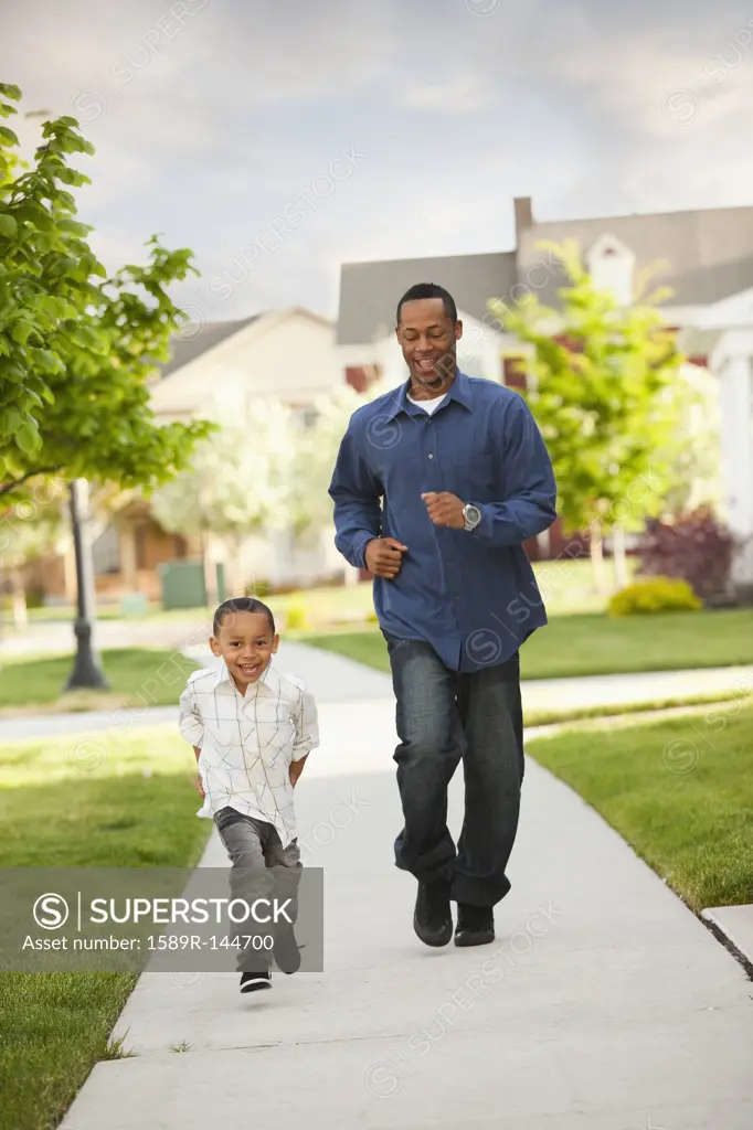 Father and son running on sidewalk