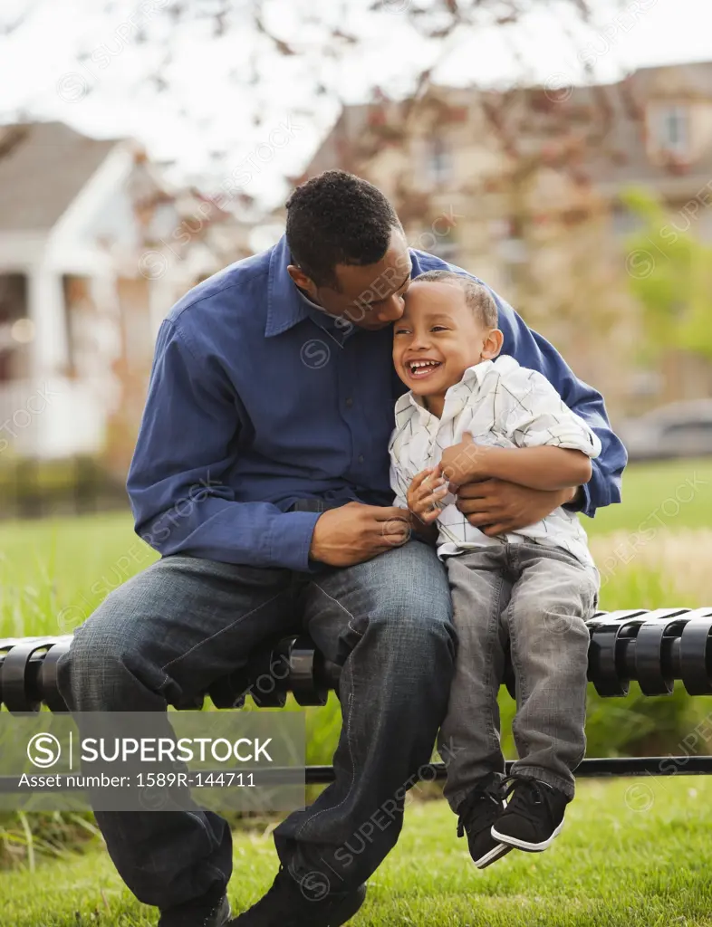 Father and son sitting together on park bench