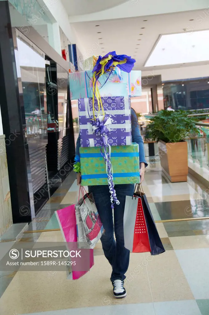Hispanic teenager carrying gifts in shopping mall