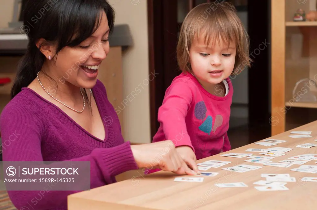 Hispanic mother and daughter playing card game