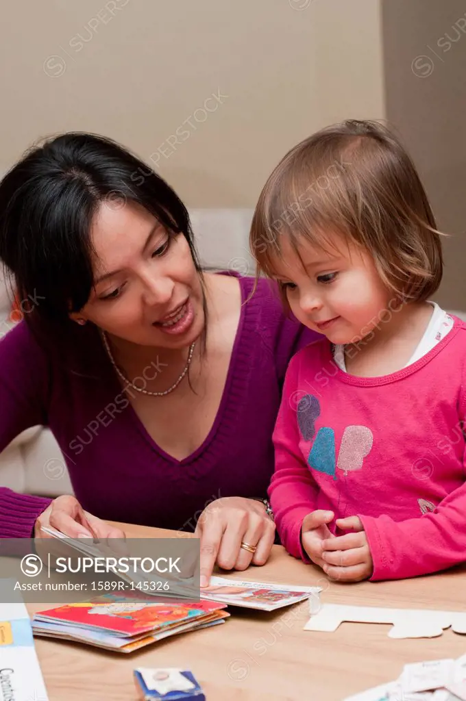 Hispanic mother reading book to daughter