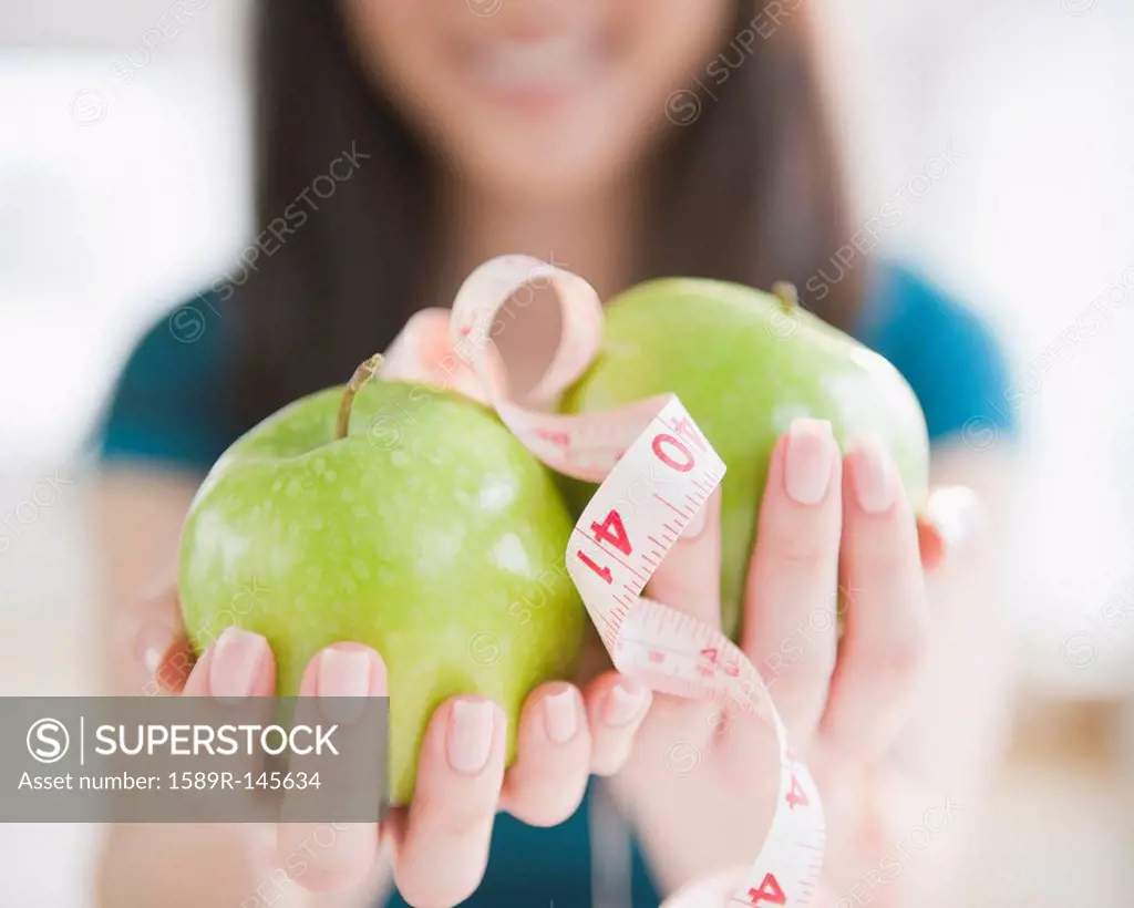 Korean woman holding apples and tape measure