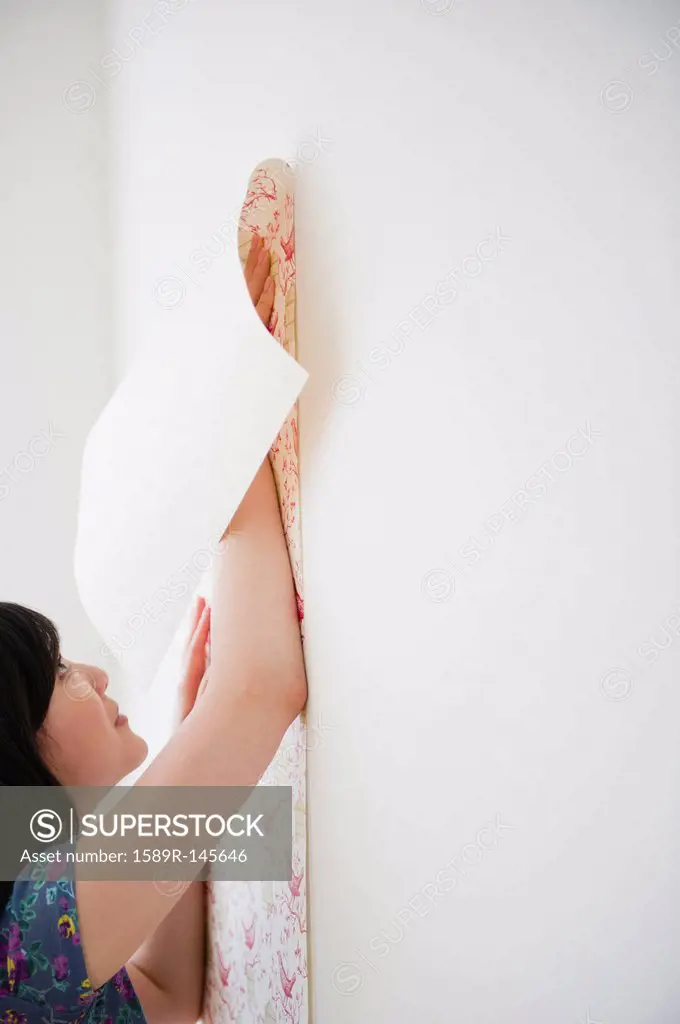 Korean woman putting wall paper on wall