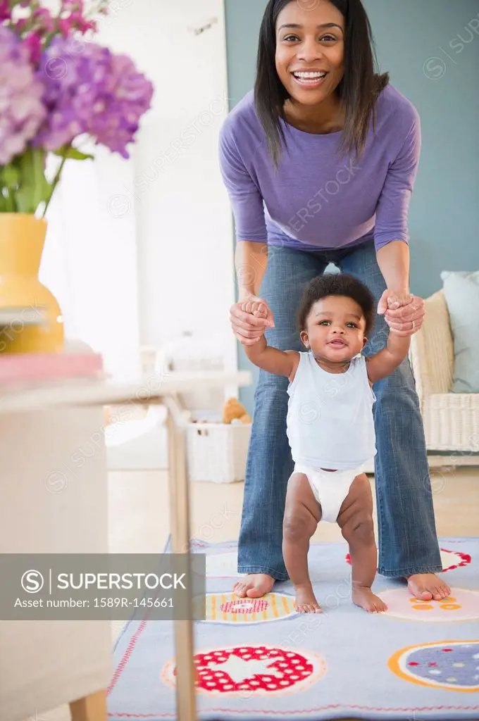 African American mother helping baby boy learn to walk