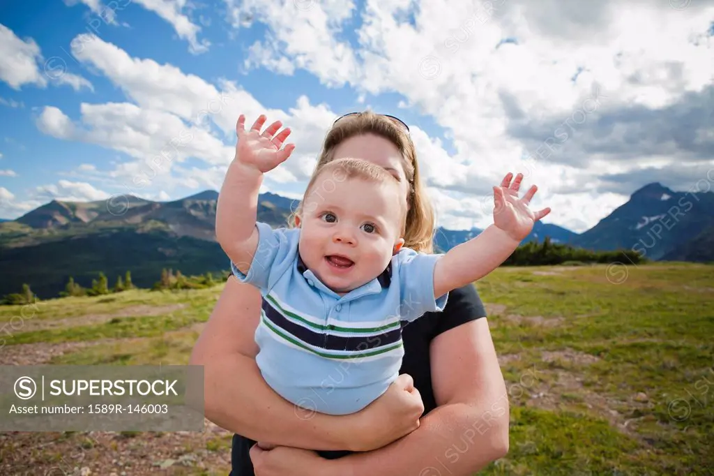 Mother holding baby in mountain field