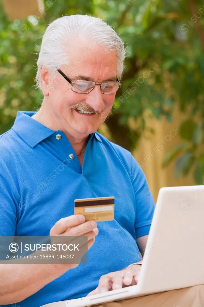 Senior Hispanic man shopping online with credit card