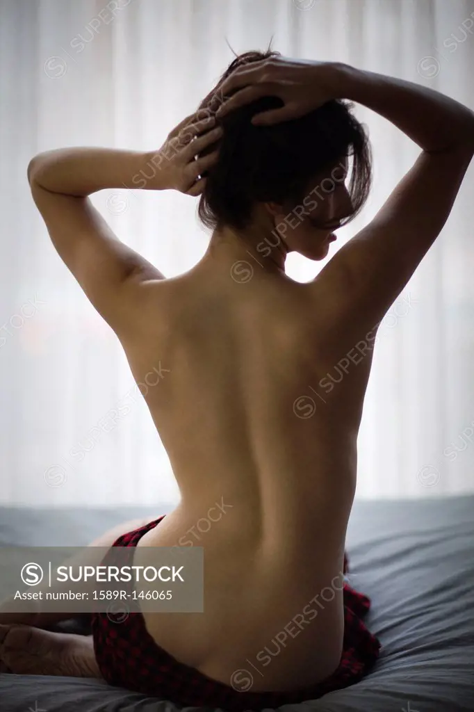 Topless Caucasian woman sitting on bed