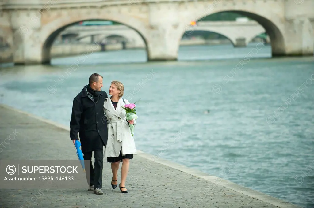 Caucasian couple walking near city river