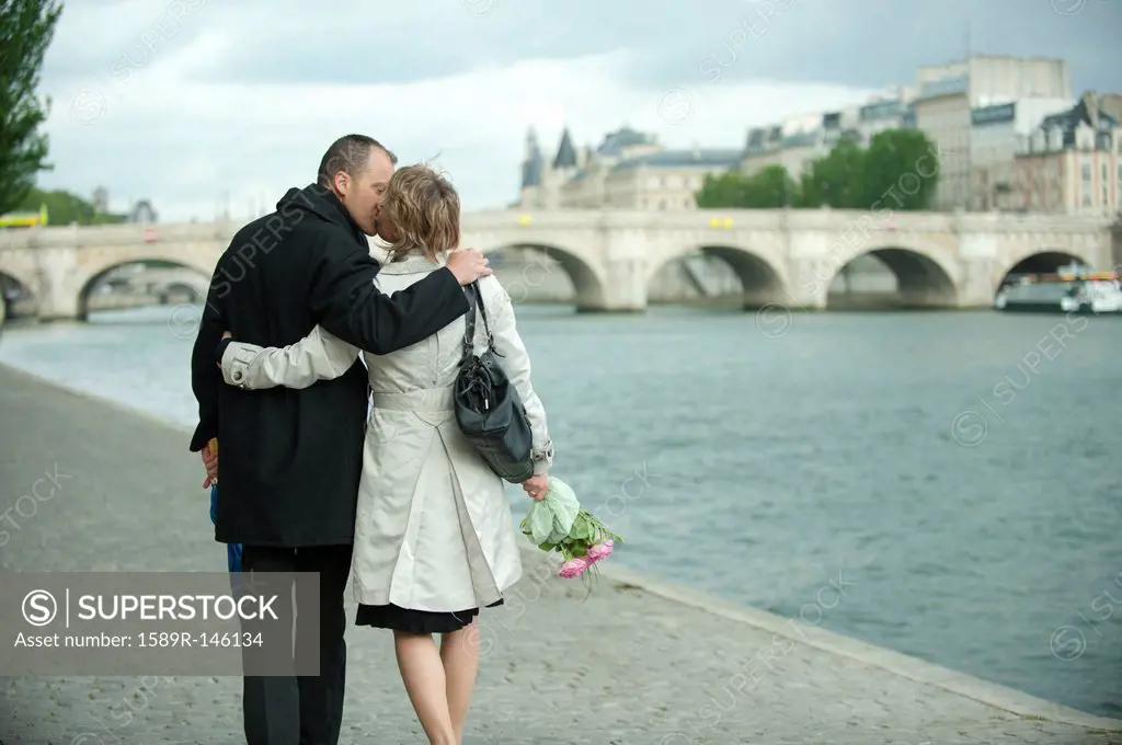 Caucasian couple kissing near city river