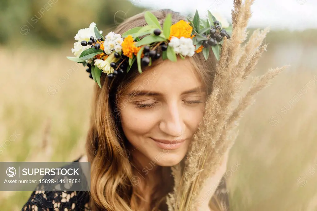 Middle Eastern woman wearing flower crown holding wheat to face