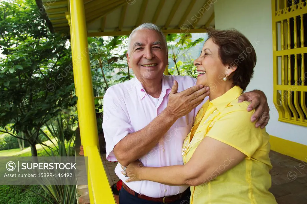 Senior Hispanic couple hugging on porch
