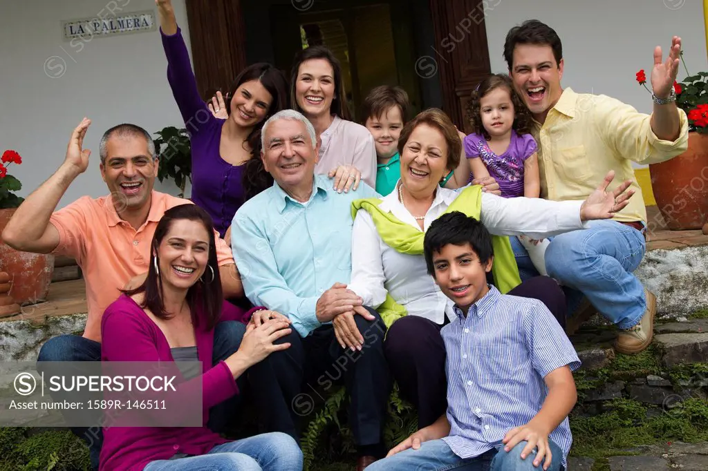 Hispanic family sitting on steps together waving