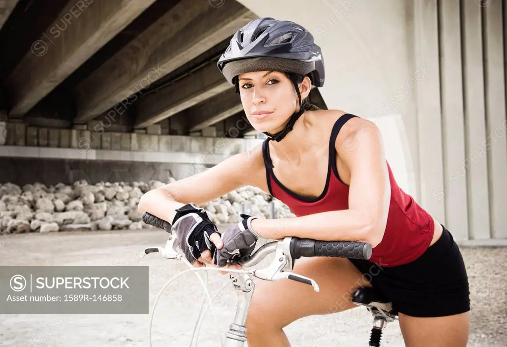 Hispanic woman sitting on bicycle in urban area
