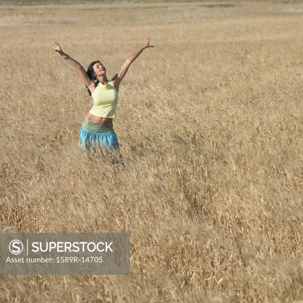 Young woman with outstretched arms in field