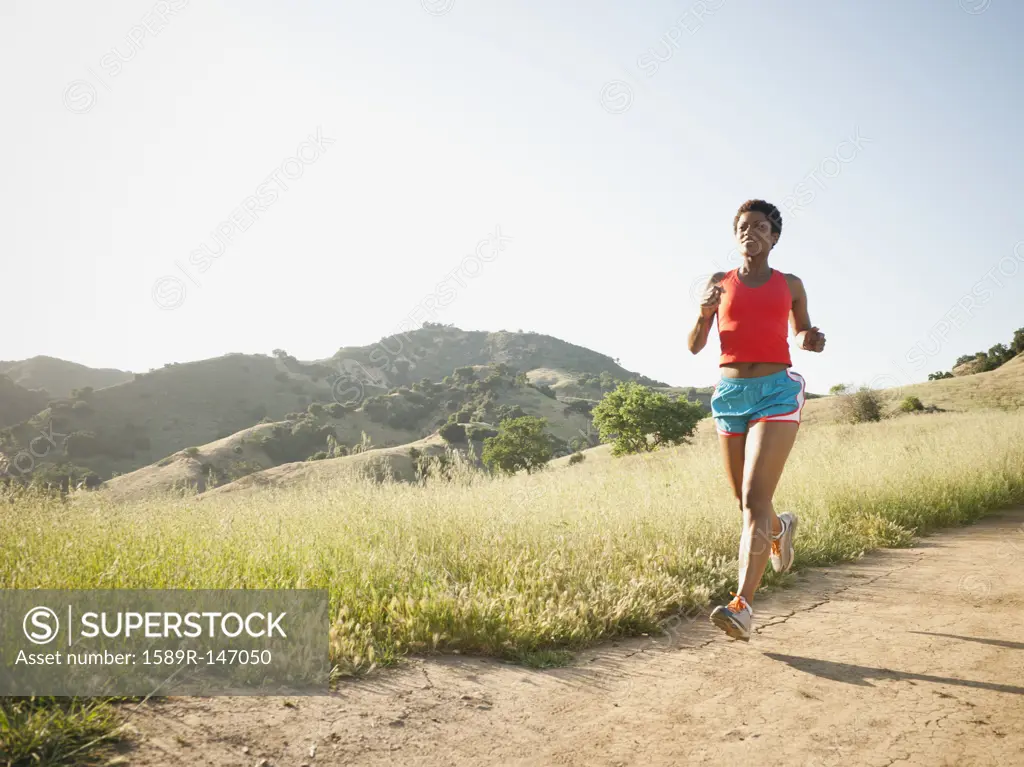 Mixed race woman running on remote trail