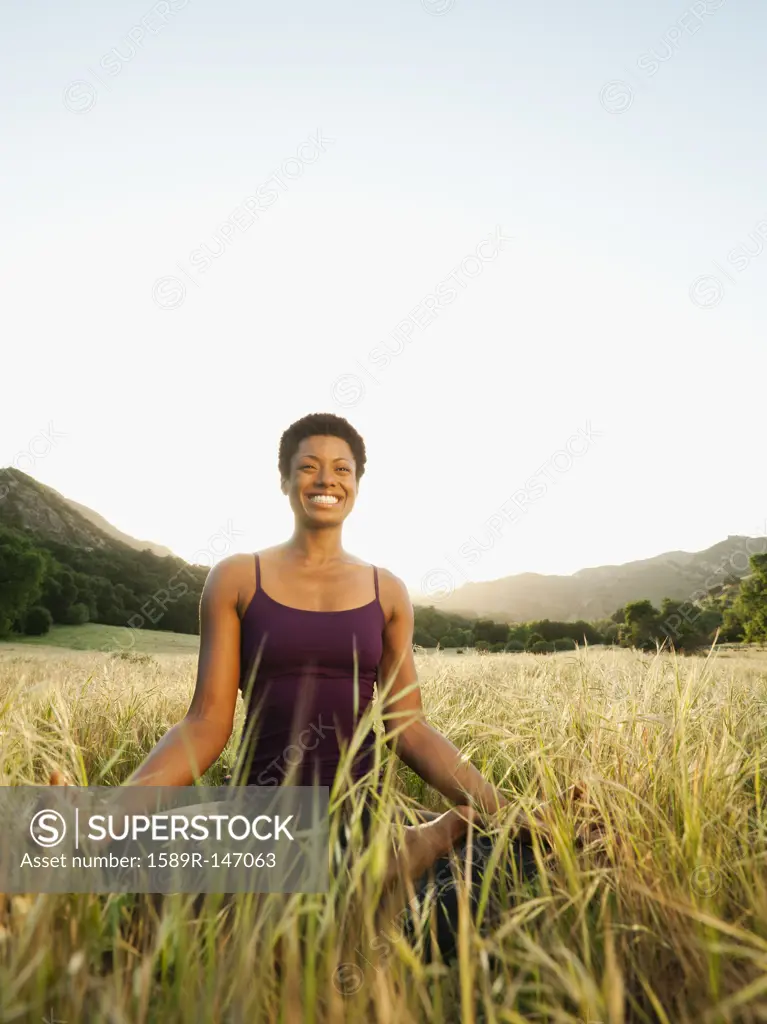 Mixed race woman practicing yoga in remote field