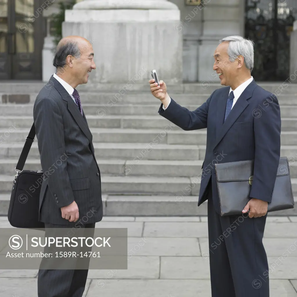 Senior Asian businessman taking picture of co-worker