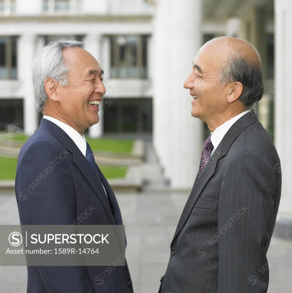 Two senior Asian businessmen laughing together