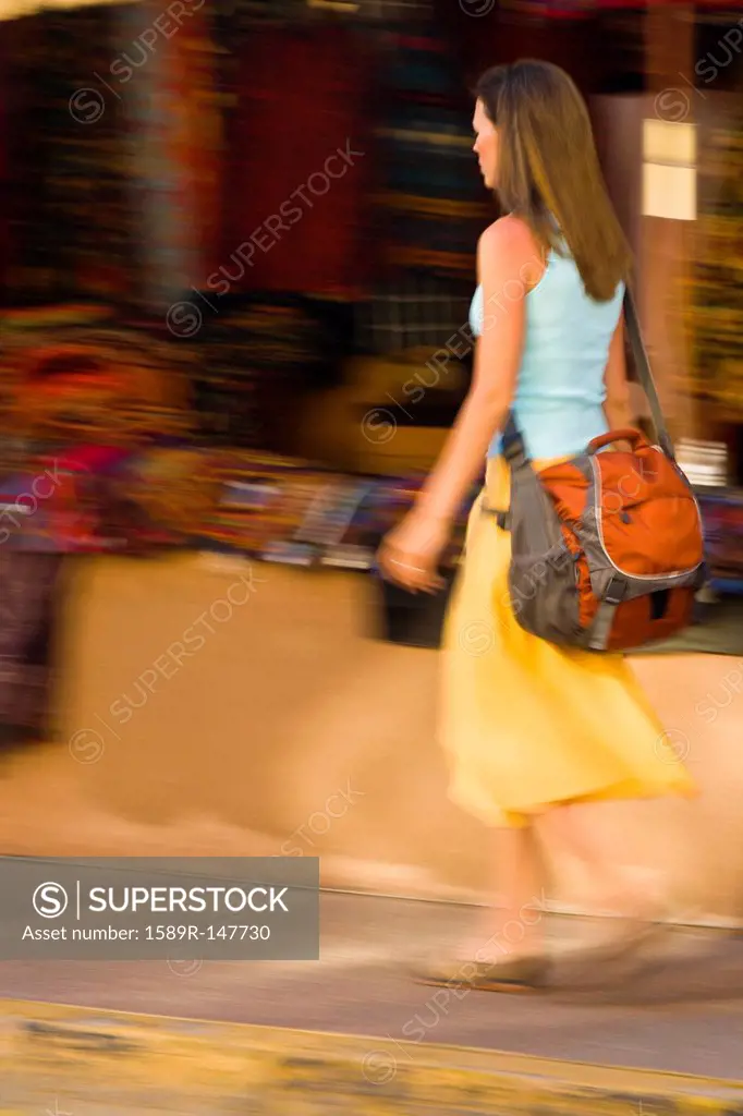 Hispanic woman walking on sidewalk